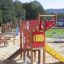 Structure de jeu colorée appelée Helicopter avec toboggan et éléments d’escalade dans un parc.