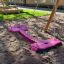 Double Seat swing sur une aire de jeux avec sol sablonneux.
