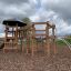 Structure de aire de jeux en bois Meru avec filets d’escalade et un toboggan.