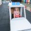 Enfant jouant dans un jouet Ambulance sur une aire de jeux extérieure.