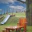 Ensemble Table Nature with a Chair and Stools en bois sur l'herbe de l'aire de jeux près d'un arbre et d'un toboggan