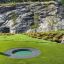 Round trampoline (80 cm) installé dans un paysage verdoyant avec un fond rocheux.