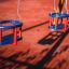 Double Baby Swing sur une aire de jeux avec sièges rouges et bleus suspendus à des chaînes.
