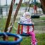 Double Baby Swing avec un bébé en tenue rose profitant de la balançoire dans une aire de jeux.