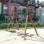 Double Swing dans une aire de jeux avec des immeubles d'habitation en arrière-plan.