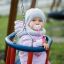 Un bébé en vêtements chauds assis sur un Double Swing.