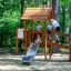 Galapagos wooden playhouse with slide et des enfants jouant dehors dans une aire de jeux en forêt