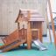 Tambora wooden playhouse with slide sur une aire de jeux avec mur d'escalade et revêtement de sécurité vert
