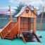 Tambora wooden playhouse with slide et mur d'escalade sur une aire de jeux