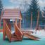 Tambora wooden playhouse with slide sur une aire de jeux extérieure