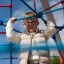 Un enfant grimpe sur l’équipement de terrain de jeu Autan climbing net dans un environnement extérieur