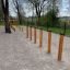 Agility Weave Poles installé en extérieur sur une surface en gravier avec des arbres en arrière-plan.