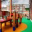 Aire de jeux extérieure avec Wetpour 45 coloré, revêtement en caoutchouc et structures de jeu en bois.