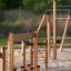 Parcours d’obstacles pour aire de jeux en bois Trim trail avec poteaux d’escalade et cordes sur sol sablonneux.
