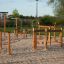 Équipement de terrain de jeu en bois Trim trail avec cordes et poutres d’équilibre sur sol sablonneux.