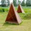 Abri de terrain de jeu Tipi Nature wooden house en bois naturel sur un champ herbeux.