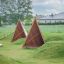 Équipement de jeu Tipi Nature wooden house en bois naturel sur un champ herbeux.