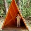 Enfant debout à l'intérieur de Tipi Nature wooden house sur une aire de jeux en forêt