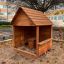 Cabane de jeu en bois avec table et tabouret installée en extérieur.