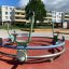 Bicycle merry-go-round sur une aire de jeux avec des immeubles d'appartements en arrière-plan.