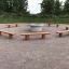Robinia bench disposé autour d'un foyer central dans un parc extérieur.