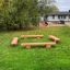 Robinia bench installé dans une aire de jeux herbeuse.