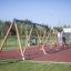 2+2 multiple swing installé sur une aire de jeux avec sol en caoutchouc et mur d’escalade en arrière-plan