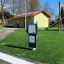 Équipement de aire de jeux interactif Gas Pump sur gazon artificiel près d'un toboggan.