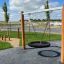 Double Swing Robinia (BNS 90) en bois dans une aire de jeux avec un siège en pneu.
