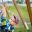 Enfant jouant sur un équipement de jeux extérieur 1+2 multiple swing.
