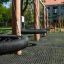 Balançoire de terrain de jeu Double Swing Robinia avec sièges ronds noirs suspendus à des poteaux en bois en extérieur
