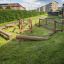 Équipement de terrain de jeu extérieur en bois Ramp sur une zone herbeuse dans un quartier résidentiel.