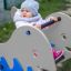 Enfant jouant sur la balançoire à ressort Whale rocking dans une aire de jeux.