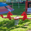 Double Pony rocking dans une aire de jeux colorée avec de l’herbe et des structures de jeu en arrière-plan