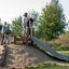 Des enfants jouent sur l'équipement de terrain de jeu Wooden Stair avec un toboggan en extérieur.