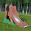 Camel single slide équipement de jeu avec un toboggan en métal dans une zone herbeuse avec des arbres à l'arrière-plan.