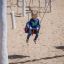 Un enfant se balance sur un Nature Double Swing dans une aire de jeux.