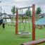 Balançoire simple sur une aire de jeux moderne avec de l’herbe verte.
