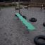 Balance panneau pour enfants sur une aire de jeux avec gravier et obstacles en pneus.