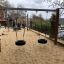 Double swing installé sur une aire de jeux sablonneuse.