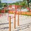 Rouge Cross Climber steel structure sur une aire de jeux avec du sable.