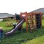 Des enfants jouent sur l’équipement de jeu Climbing Kiosk Nature dans un jardin.