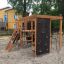 Structure de jeu Climbing Kiosk Nature avec cadre en bois, filets d’escalade et mur d’escalade dans un bac à sable