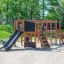 Enfants jouant sur la structure de l’aire de jeux Romping Center Nature avec toboggans et éléments d’escalade