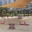 Double Seesaw dans une aire de jeux urbaine moderne avec une voile d’ombrage au-dessus.