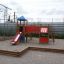 Aire de jeux extérieure avec un toboggan rouge et une tour.