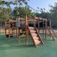 Aire de jeux en bois Square Play Nature avec toboggans, structures d’escalade et tunnels pour enfants.