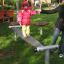 Enfant en équilibre sur l’équipement de jeu Surf Board avec l’aide d’un parent.