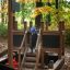 Un enfant jouant sur une structure de jeu Small Ship Nature dans une forêt d’automne.