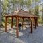 Abri en bois Long Firehouse avec tables de pique-nique et grill dans une forêt.